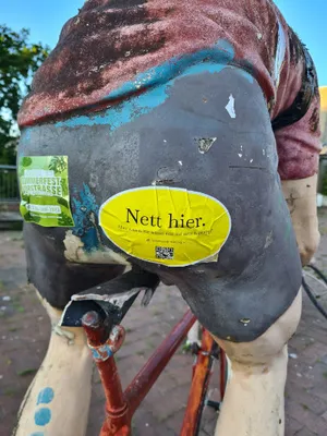 Ein Nett hier Sticker der an einem Fahrradfahrer klebt.